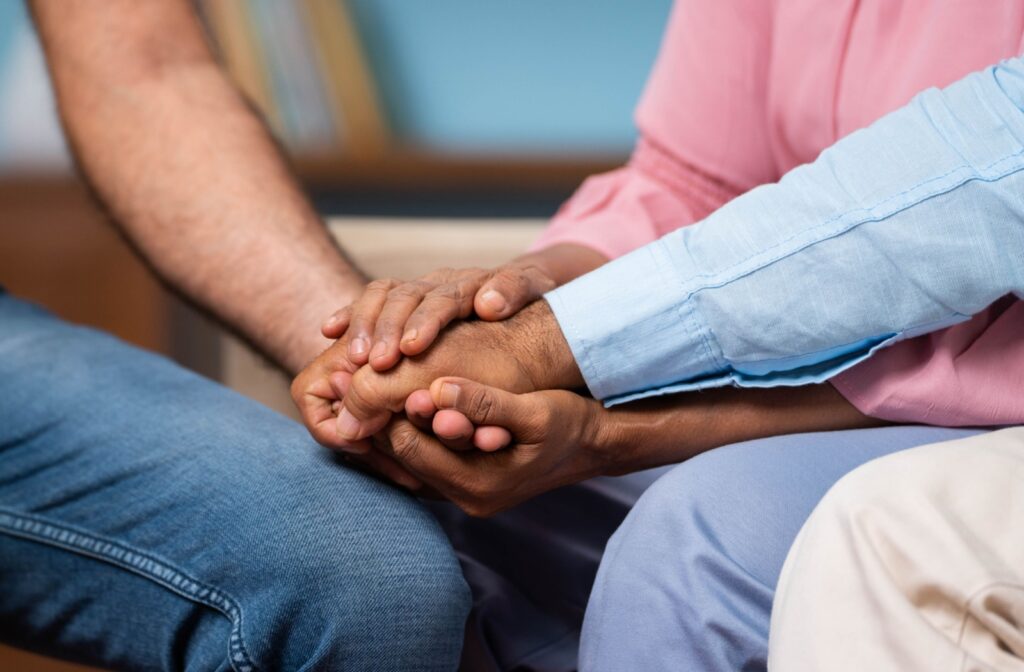 3 family members hold hands supporting a senior parent with memory loss.