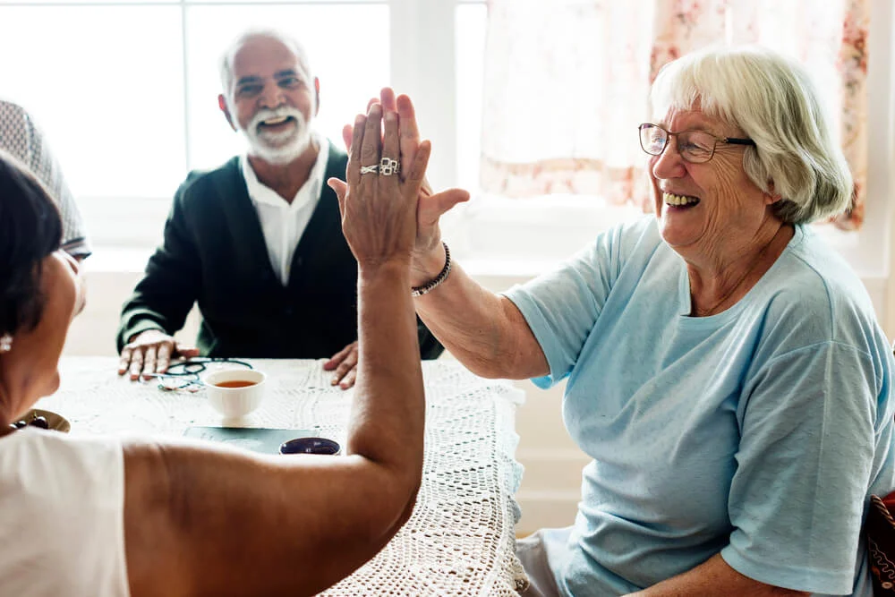A group of elderly people smile as they play a game in a senior independent living facility in mn