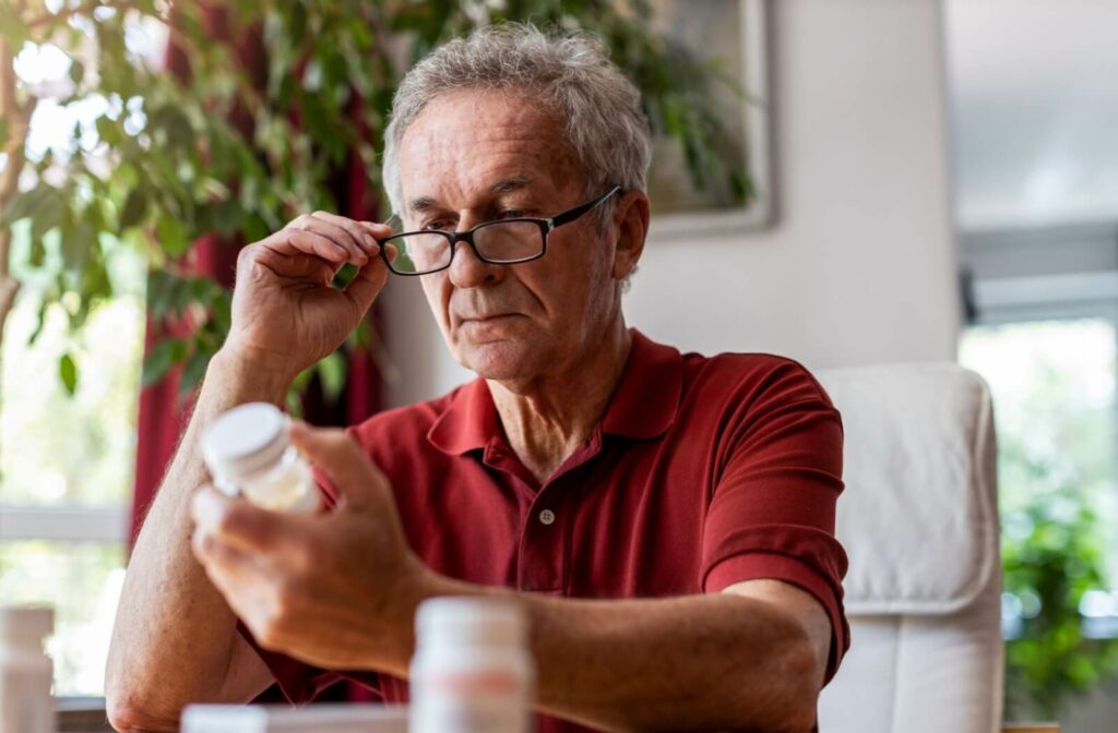 An older adult closely examines the label of a container of pills, trying to remember whether they took their medication